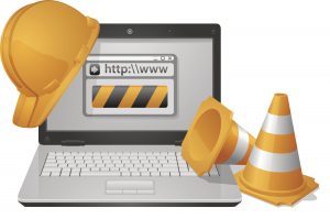 Laptop with construction helmet and traffic cones.